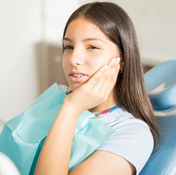 Teen girl with braces holding her cheek