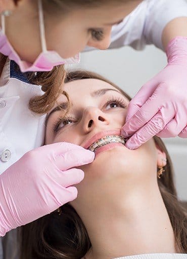 Young woman having orthodontic wire repaired