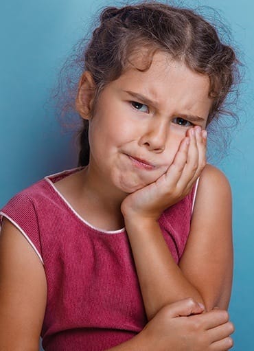 Young girl holding cheek in pain