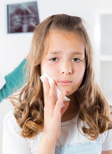 Young girl holding cold compress to cheek