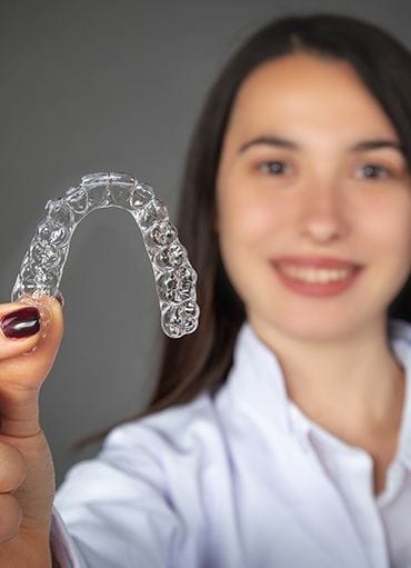 Woman holding out clear Invisalign tray