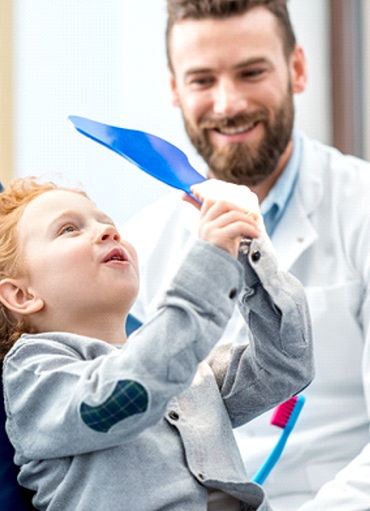 Happy child visiting dentist, admiring results of Myobrace