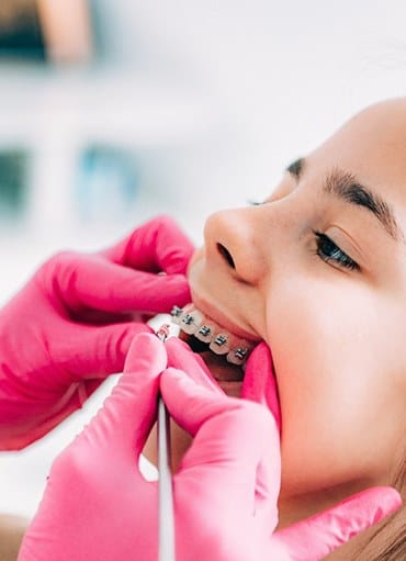 Dentist checking little girl's braces at appointment