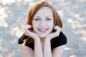 pretty young woman with traditional braces smiling at camera