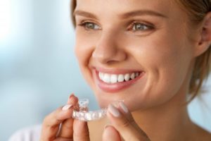 Smiling woman holds Invisalign in Glenpool