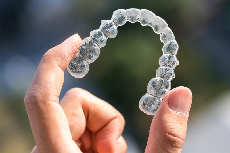 an up-close look at a person holding an Invisalign aligner in their hand