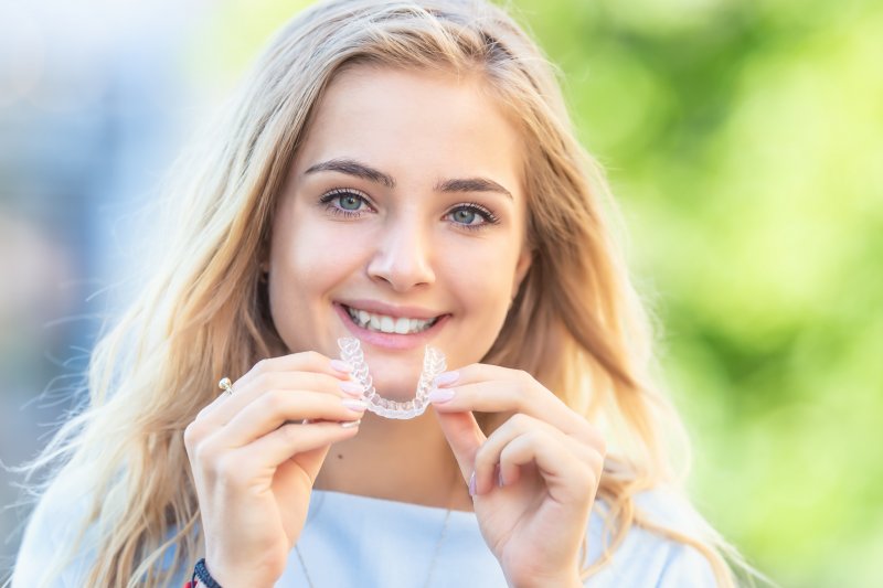 young woman holding Invisalign aligner