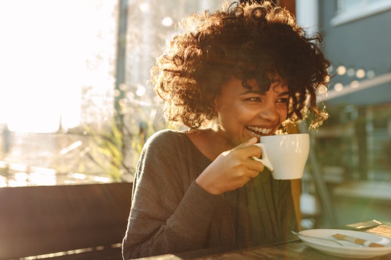 young woman smiling and drinking coffee