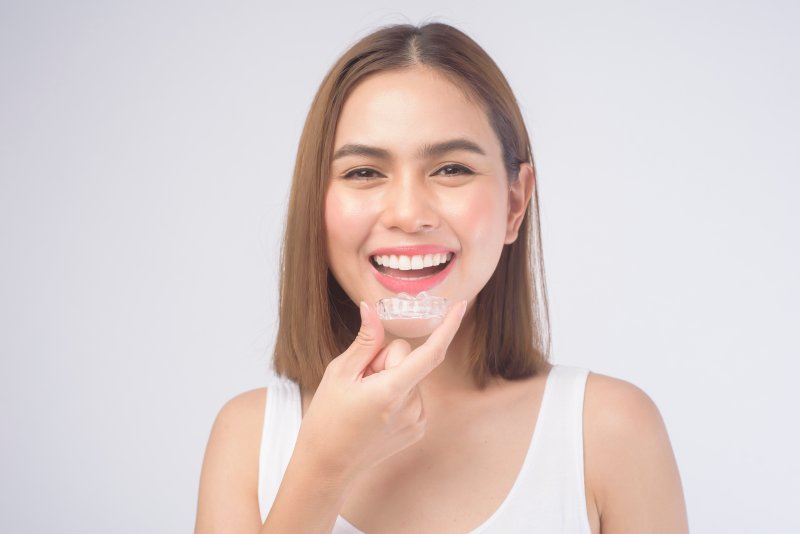 young woman holding her Invisalign aligner