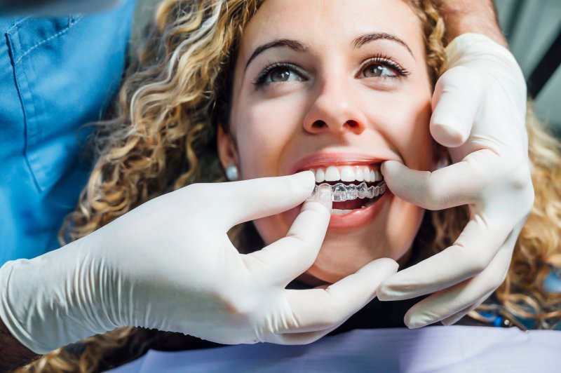 young woman putting on an Invisalign aligner